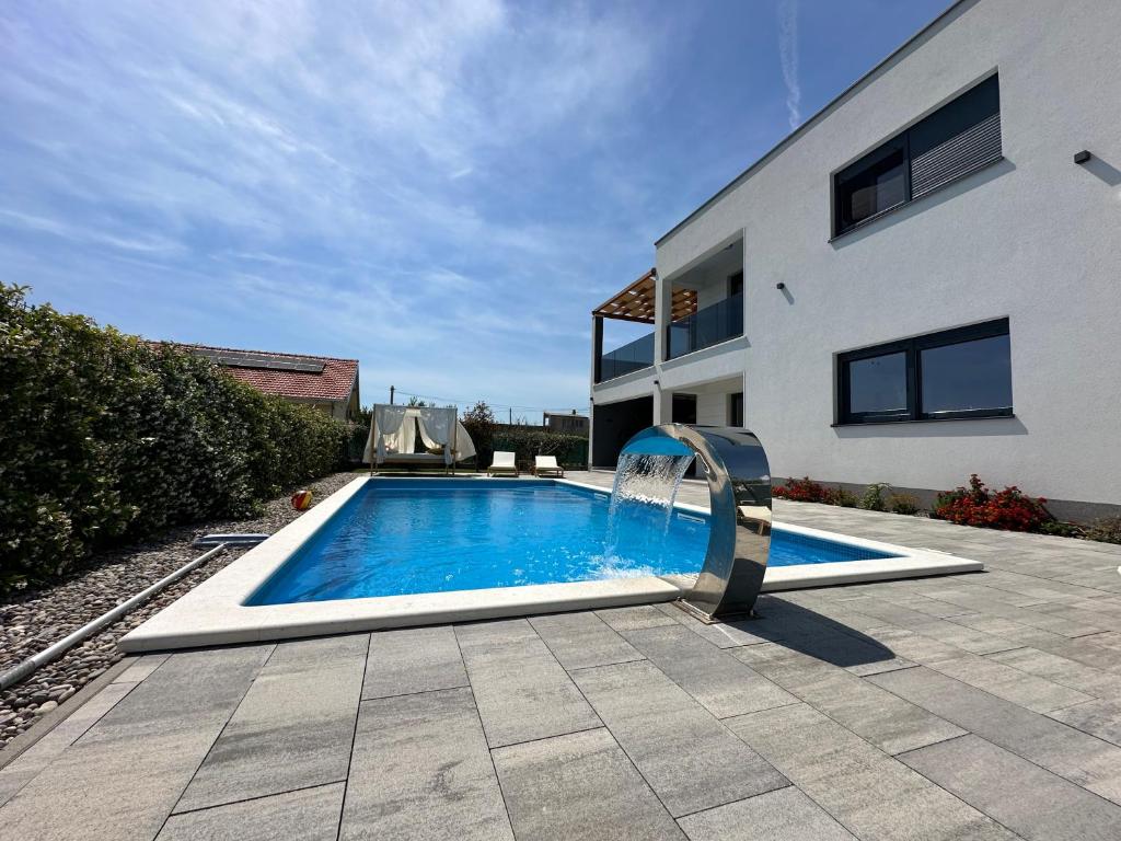 a swimming pool with a water slide in front of a house at Villa C'est la vie in Kaštela