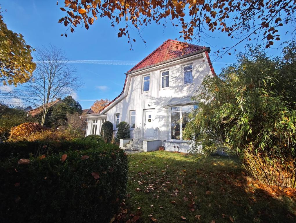 an old white house with a red roof at Trentsee Chalet in Malente