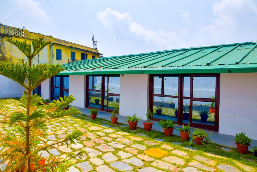 a house with a green roof and potted plants at The Valley View Homestay in Lansdowne