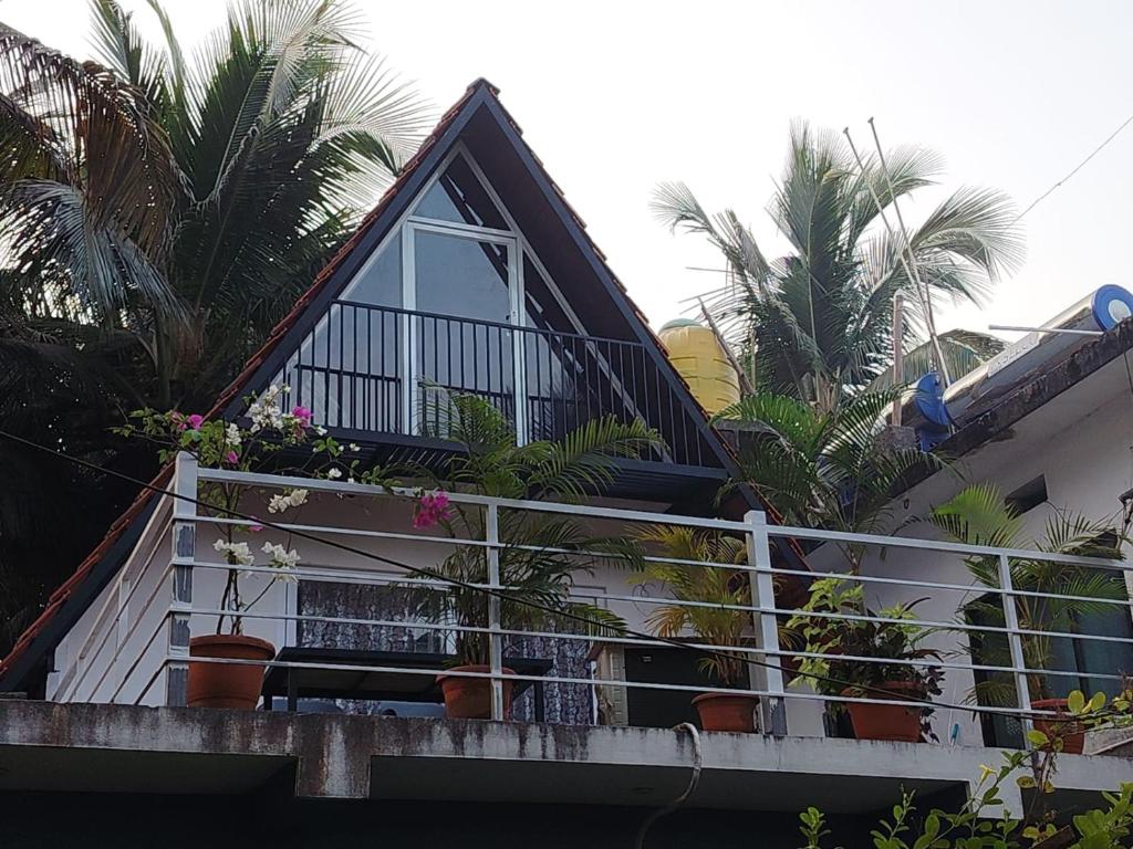 a balcony of a house with potted plants on it at Arundekar's Cottage in Gokarna