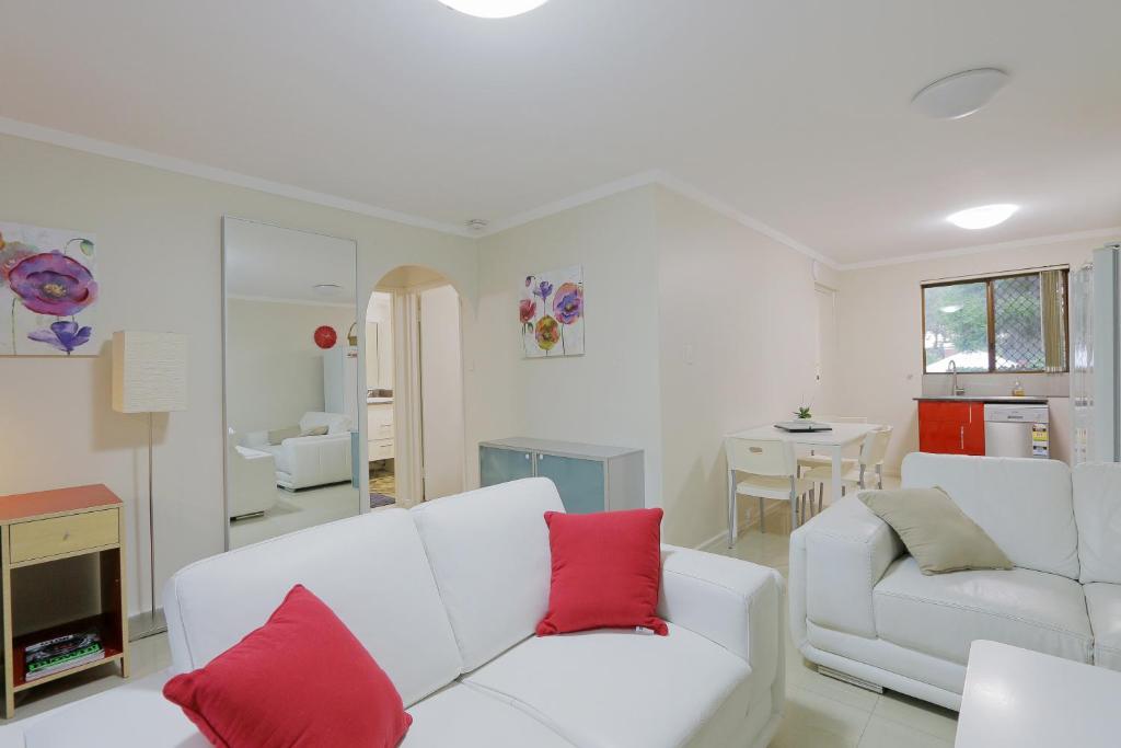 a living room with a white couch and red pillows at Parkline Apartments Perth in Perth