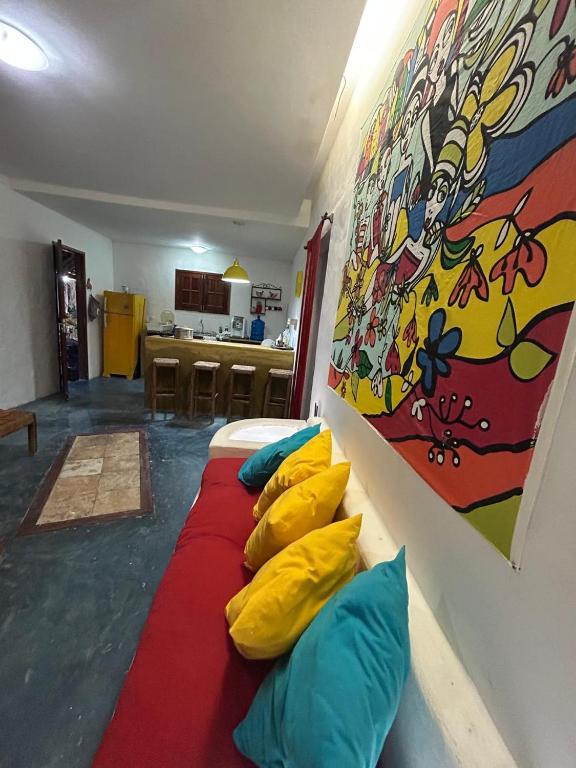 a room with a bed with pillows and a painting on the wall at Casa Bosque Guajiru in Trairi