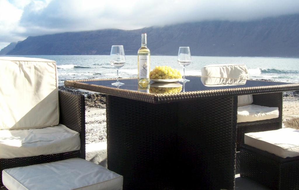 カレタ・デ・ファマラにあるAbsolute Beachfront House IIのテーブル(椅子2脚付)、ボトル1本、ワイングラス