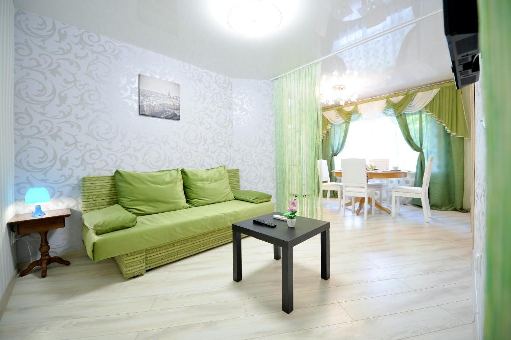 sala de estar con sofá verde y mesa en Five Stars Park Gagarina en Chelyabinsk