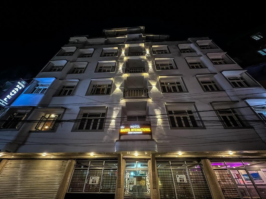 a white building with lit up windows at night at Hotel Marvel International And Restaurant in Darjeeling