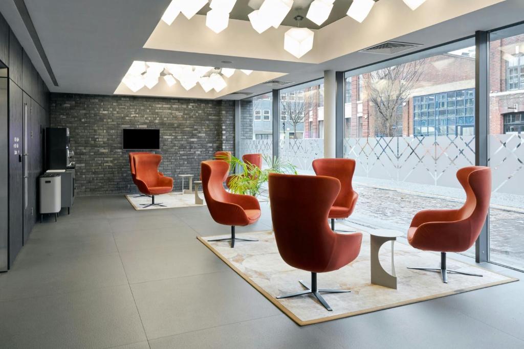 a waiting room with orange chairs and a table at Four Points Flex by Sheraton Birmingham Jewellery Quarter in Birmingham