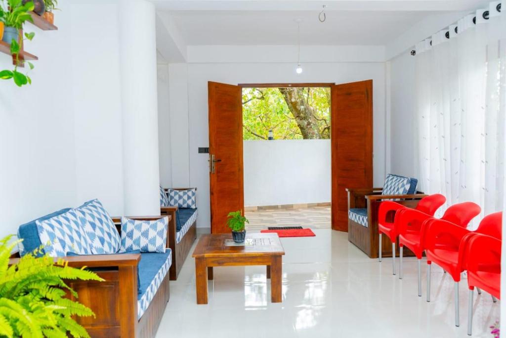 a living room with red chairs and a table at Ella Flower Zone Holiday Resort in Bandarawela