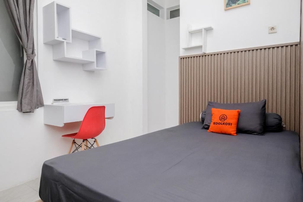 a bedroom with a bed and a red chair at Omah Ninten Syariah Laweyan RedPartner in Solo