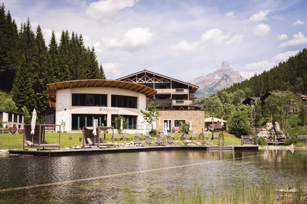 a building next to a lake in front of a mountain at Landhotel Alpenhof Filzmoos in Filzmoos