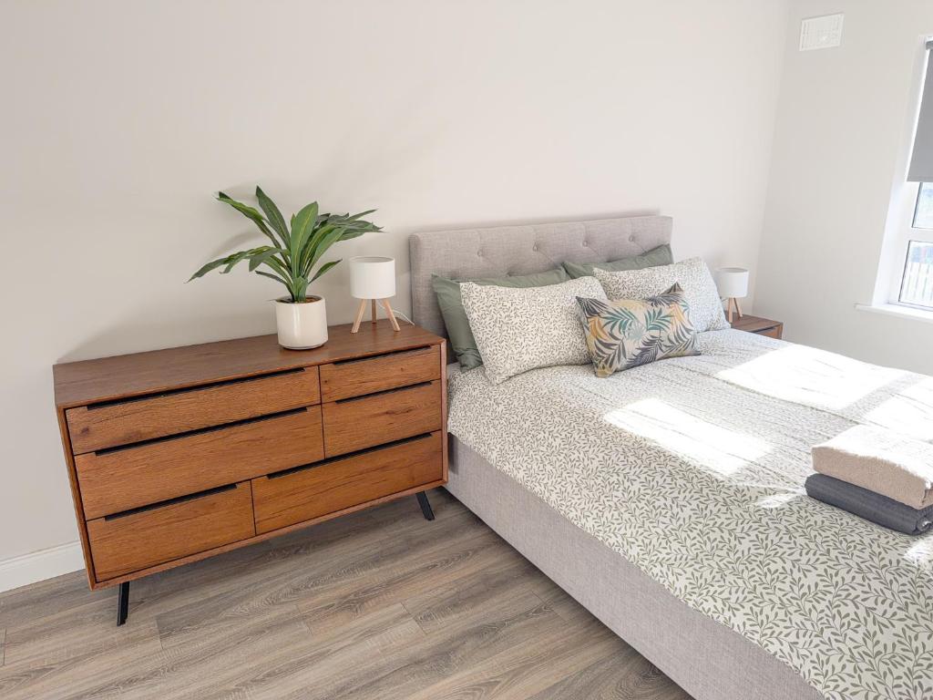 a bedroom with a bed and a dresser with a plant on it at Luxury 2-Bedroom Apartment Overlooking the Beach in Bundoran