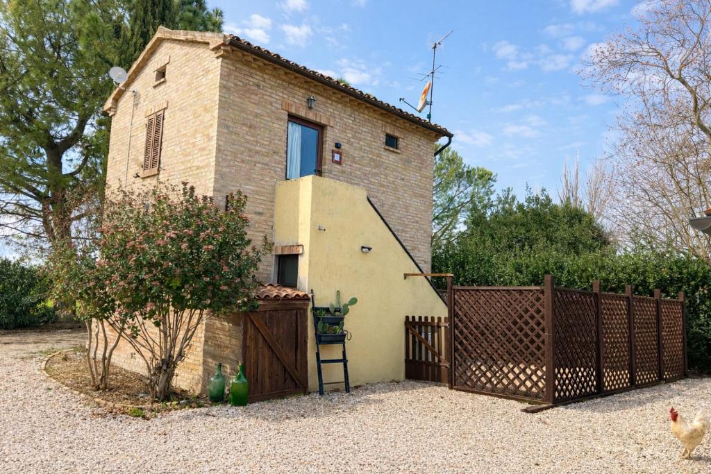 a brick house with a fence and a gate at fattoria Coppetella Cemani in Molino dʼAgugliano