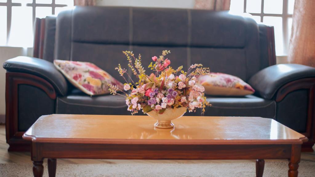 a vase of flowers sitting on a coffee table at Arusha Oasis Executive Residence in Arusha
