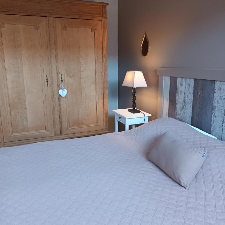 a bedroom with a white bed with a wooden cabinet at Le Relais De La Motte in Soignies