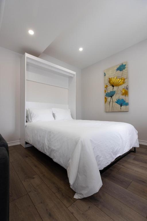 a white bedroom with a large bed and a painting at Cozy Cove Retreat, Private Suite with Separate Entrance Near Friday Harbour, Barrie & Lake Simcoe in Innisfil