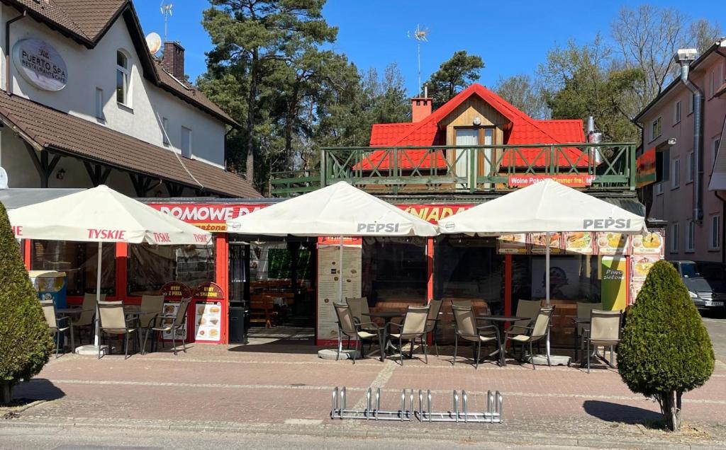 a restaurant with chairs and umbrellas on a street at PanTuszka Pokoje in Pobierowo