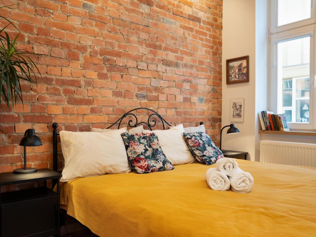 a bedroom with a brick wall and a bed with towels at Apartamenty Bydgostia Dworzec in Bydgoszcz