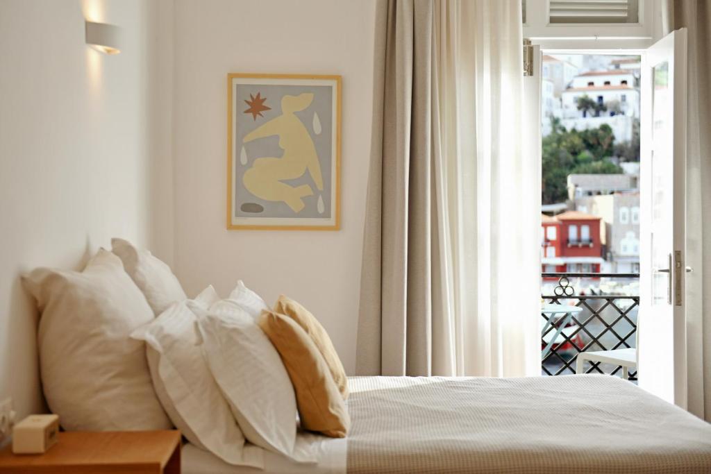 een slaapkamer met een bed met witte kussens en een raam bij NESEA VIEW Boutique Apartments in Hydra