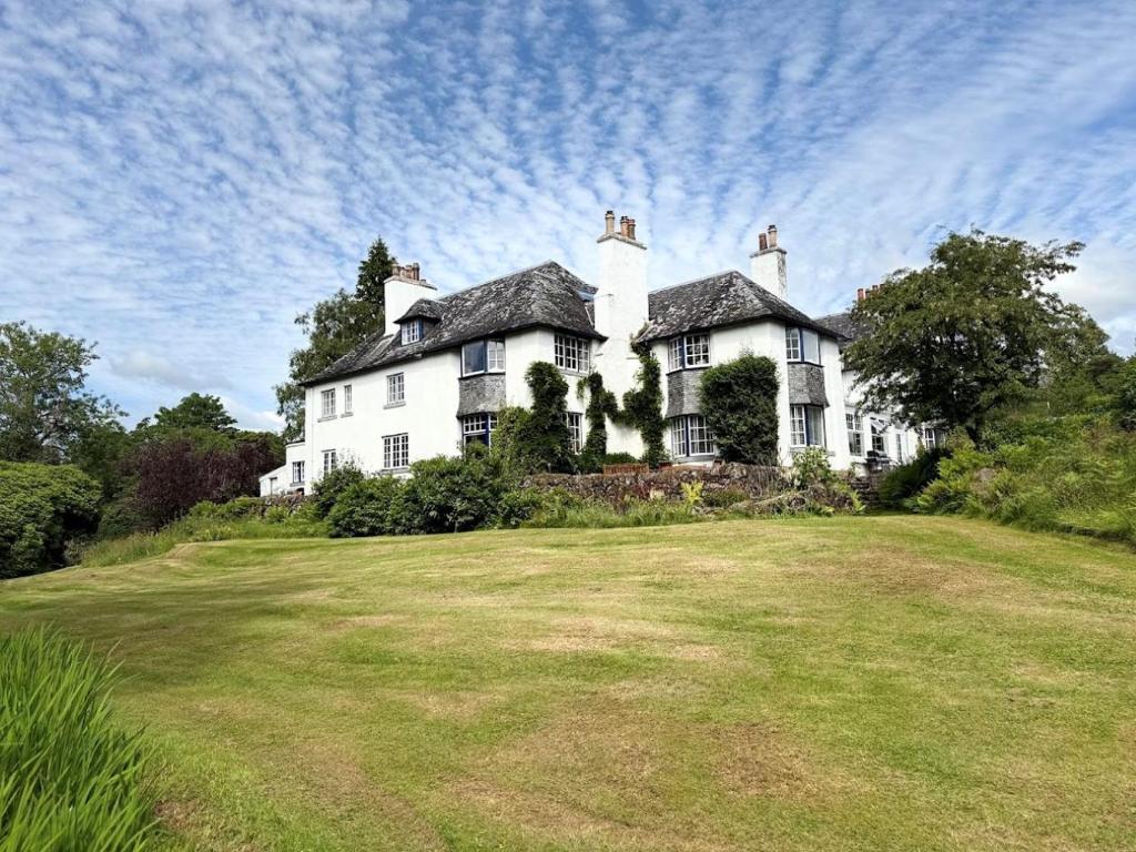 a large white house on top of a grass field at Lonan Country House and Gardens in Taynuilt