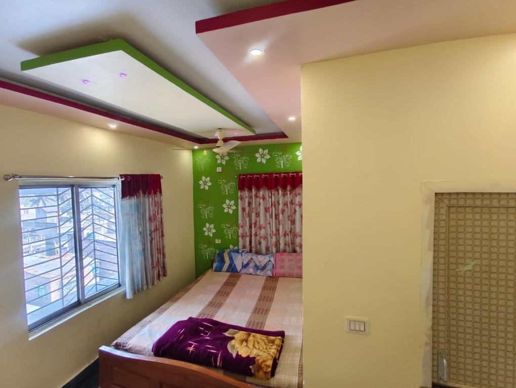 a bedroom with a bed in a room with green walls at Maa durga lodge in Navadwīp