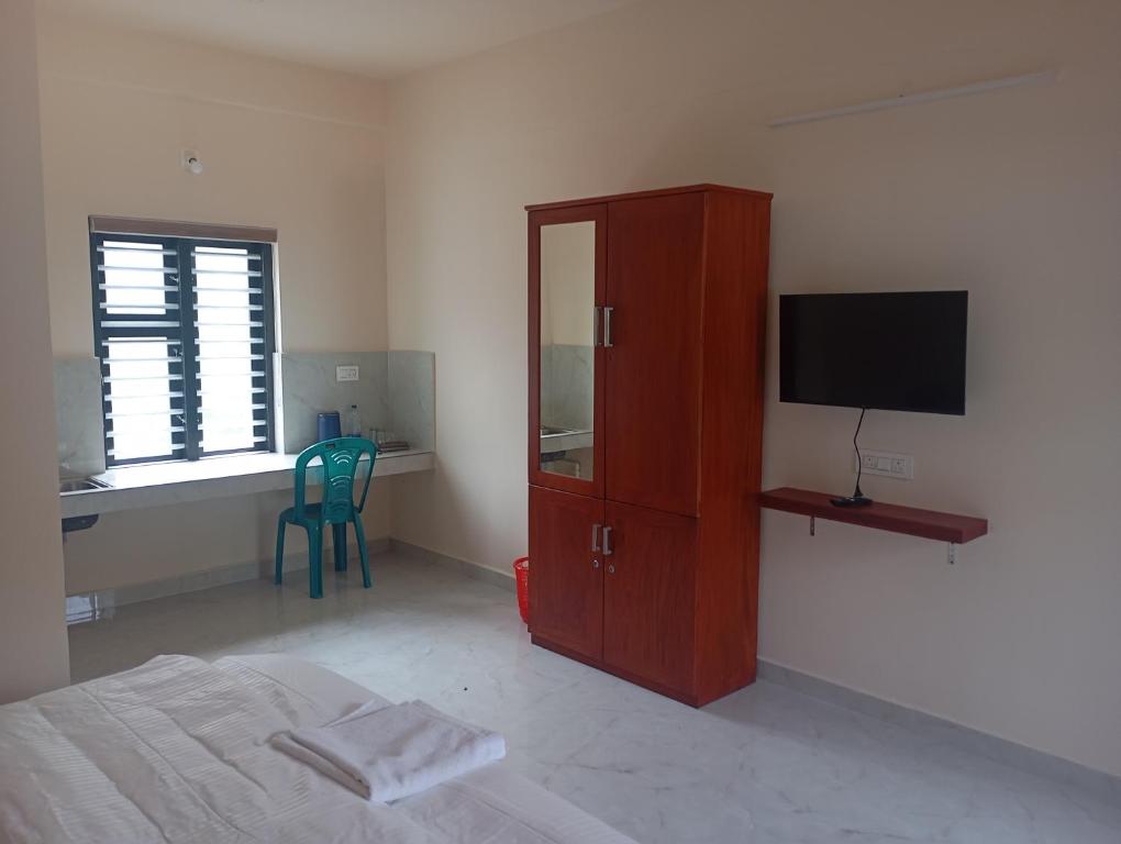 a bedroom with a bed and a cabinet with a television at PURAYIL Rooms in Kozhikode
