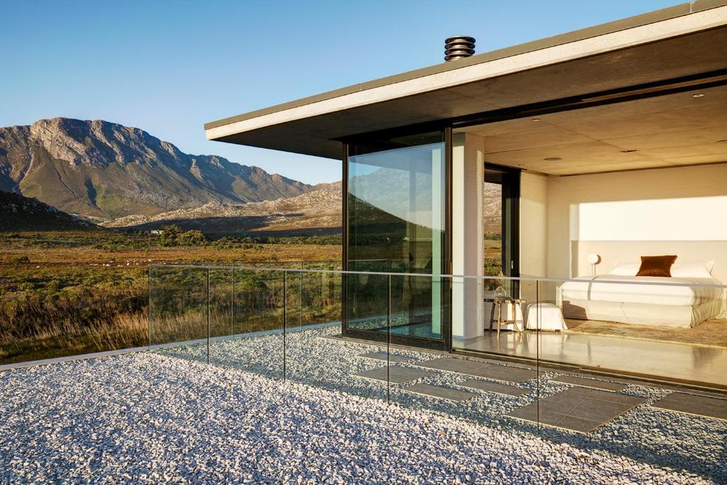 a glass house with a view of the mountains at Restio River House in Pringle Bay