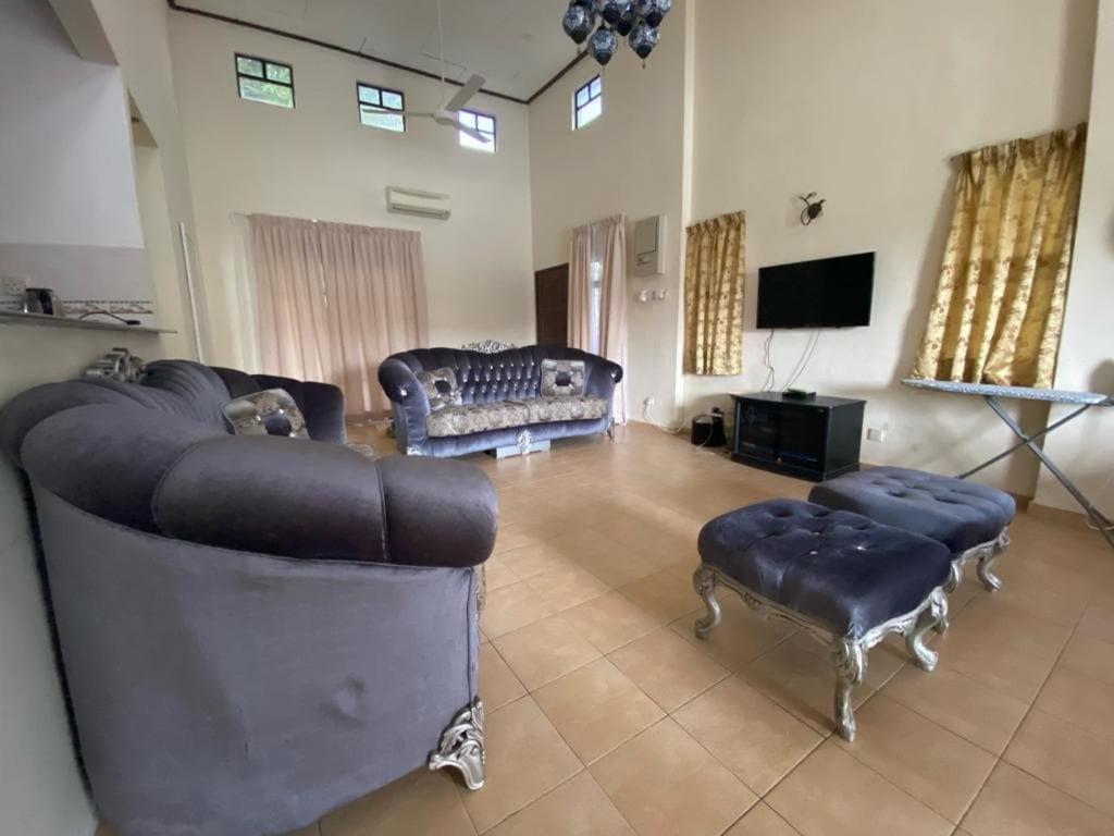 a living room with two couches and a tv at La villa June by Juniar Place in Kampong Ulu Pegoh