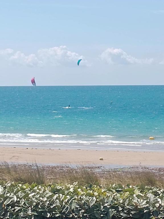 Beach Villa في Saint-Germain-sur-Ay: شخص يمارس رياضة ركوب الأمواج الشراعية في المحيط على الشاطئ