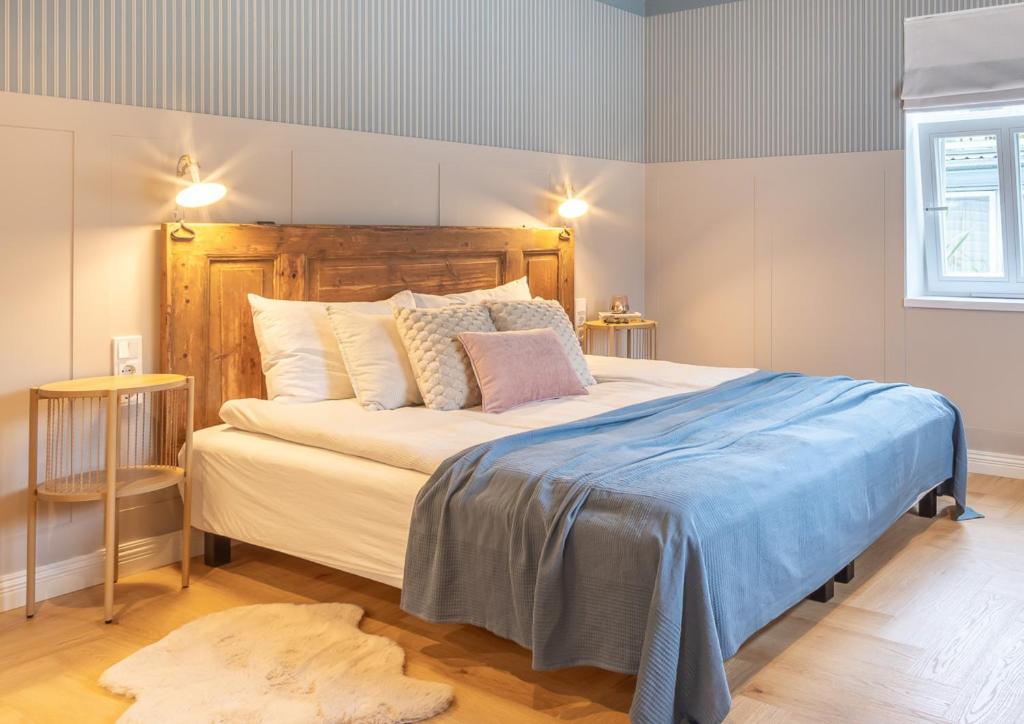 a bedroom with a large bed with a wooden headboard at Alice Backyard Holiday Home - Apartments, Rooms & Exclusive Cave Saunas in Pärnu
