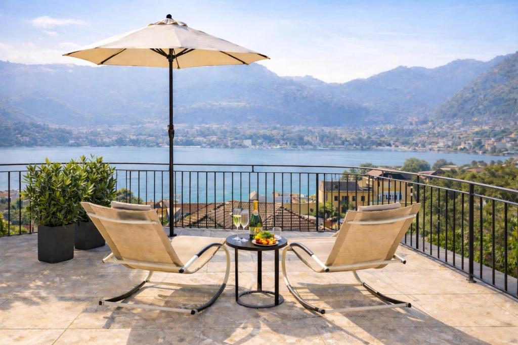 a patio with two chairs and a table with an umbrella at Villa Miranda Luxury Como Lake View Penthouse with Panoramic Terrace in Como