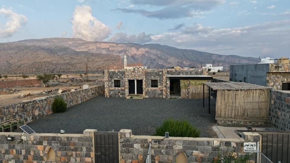 an old stone building with a mountain in the background at house of the cloud jabal shams in Sa‘ab Banī Khamīs