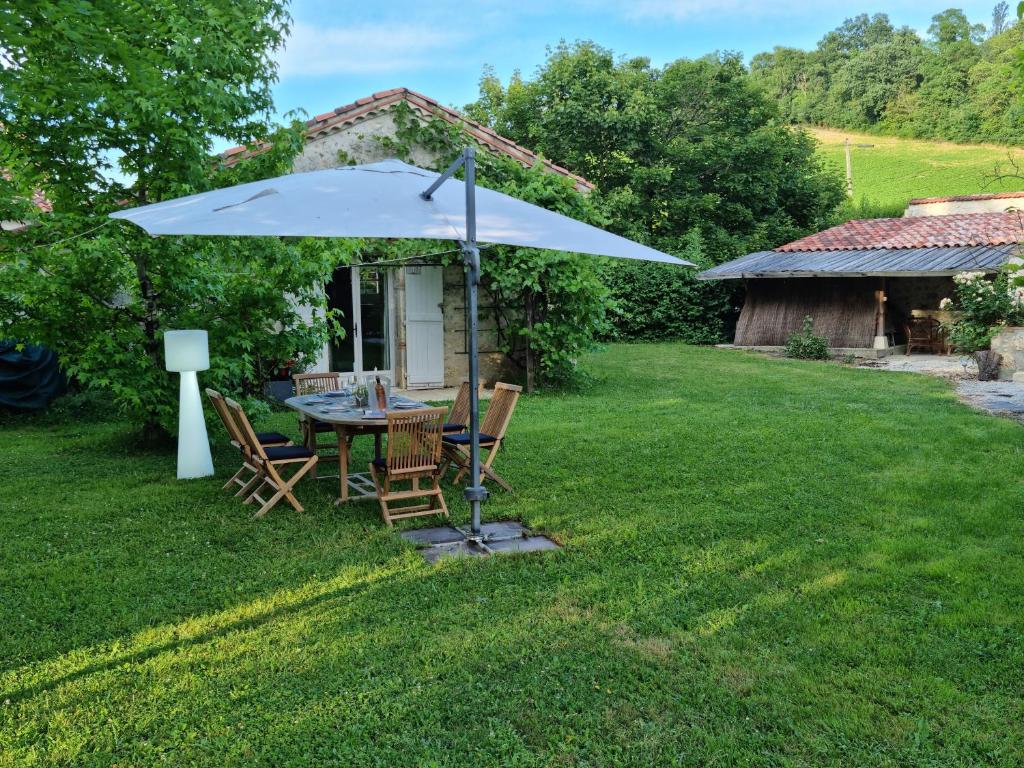 a table and chairs under an umbrella in a yard at Prouyssou in Beauville
