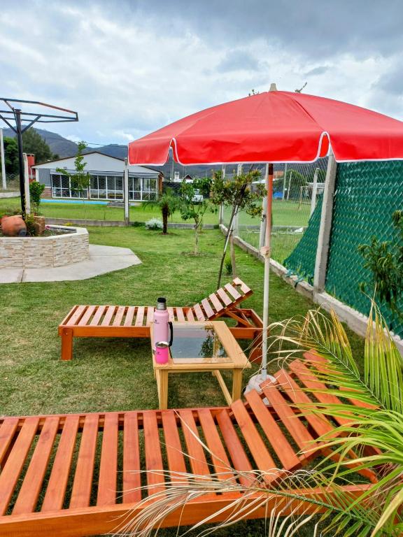 a red umbrella and a bench and a table at Los Adobes in Cerrillos