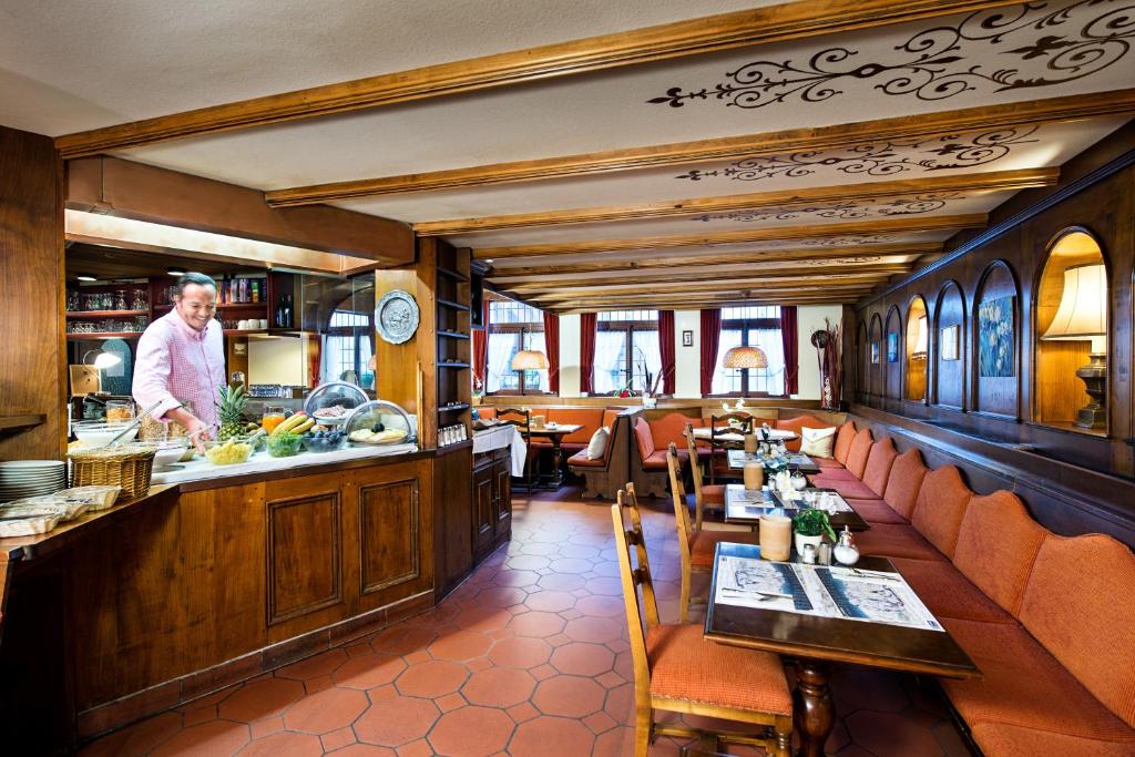 a restaurant with a chef standing at the counter at Le Petit CHARME-INN in Zermatt