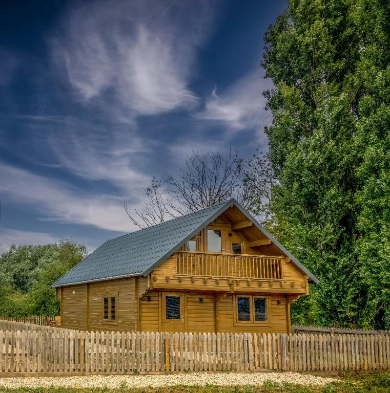 a wooden house with a fence in front of it at Buzzards Retreat in Larling