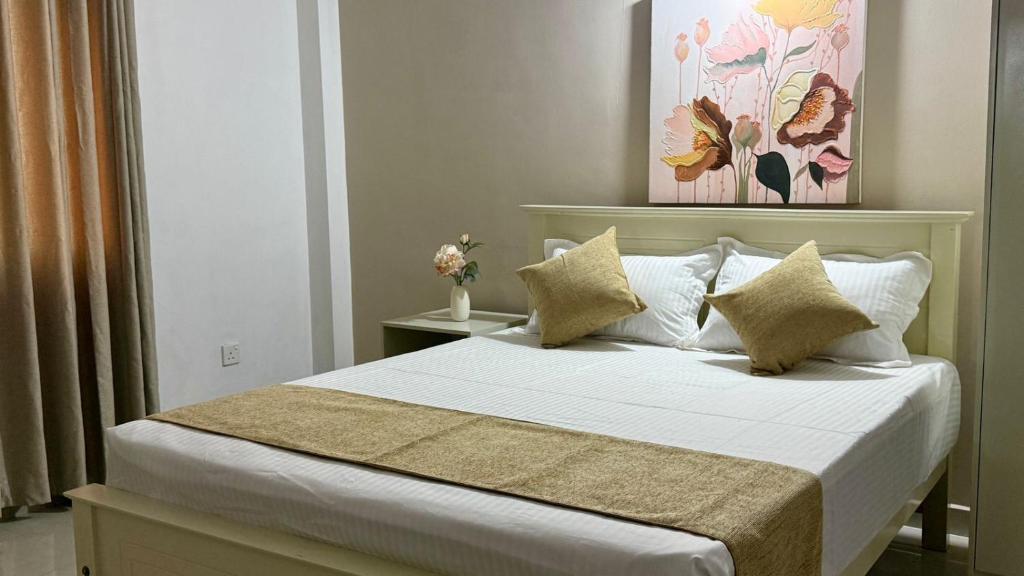 a bedroom with a large bed with white sheets and pillows at Opal Heights in Gampaha