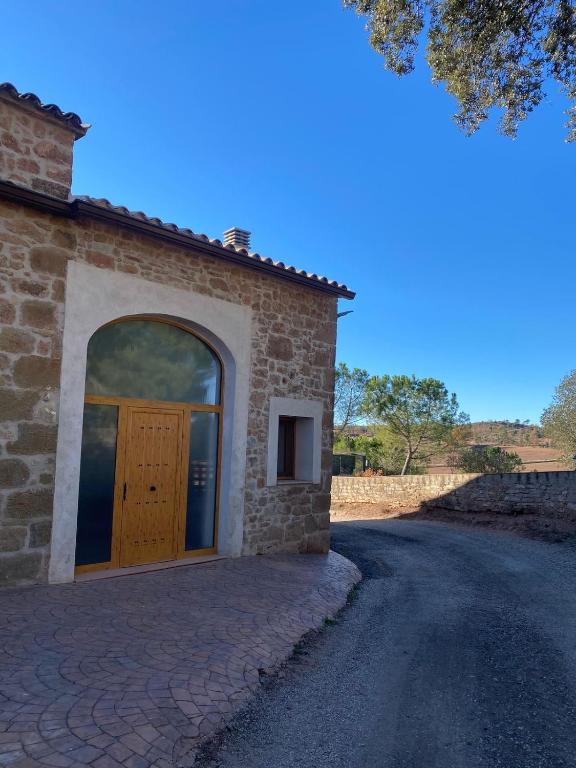 a brick building with a wooden door on a road at Dúplex les Coromines in San Pedro Sallavinera