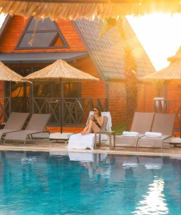 a woman sitting in a chair next to a swimming pool at Palm Garden in Korucuk