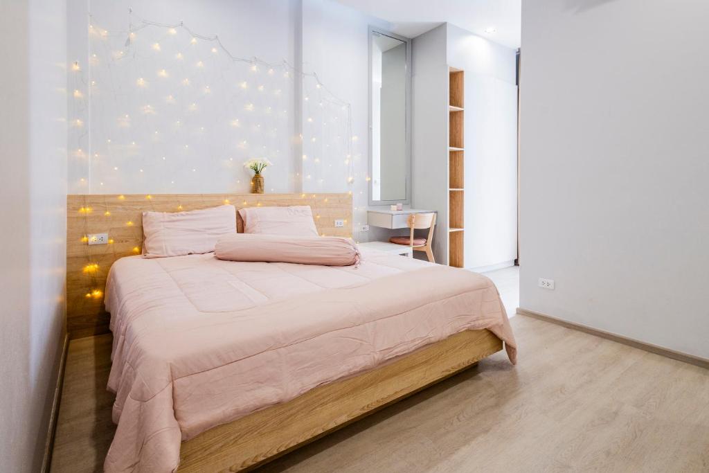 a bedroom with a large bed with lights on the wall at SPACIOUS AND BRIGHT 2BR TownHouse7 MonkeyHill in Ban Sam Kong