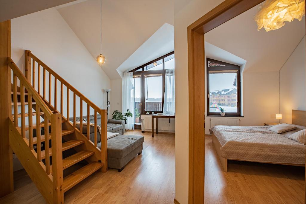 a bedroom with a bed and a staircase in a room at Lara Mezonet Tatry in Veľká Lomnica