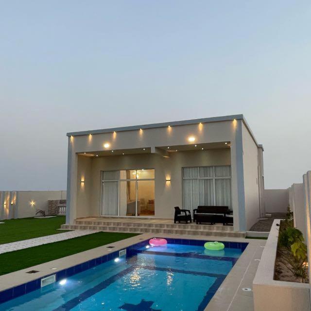 a house with a swimming pool in front of it at شالية مزايا الاشخرة in Al Sharqiyah