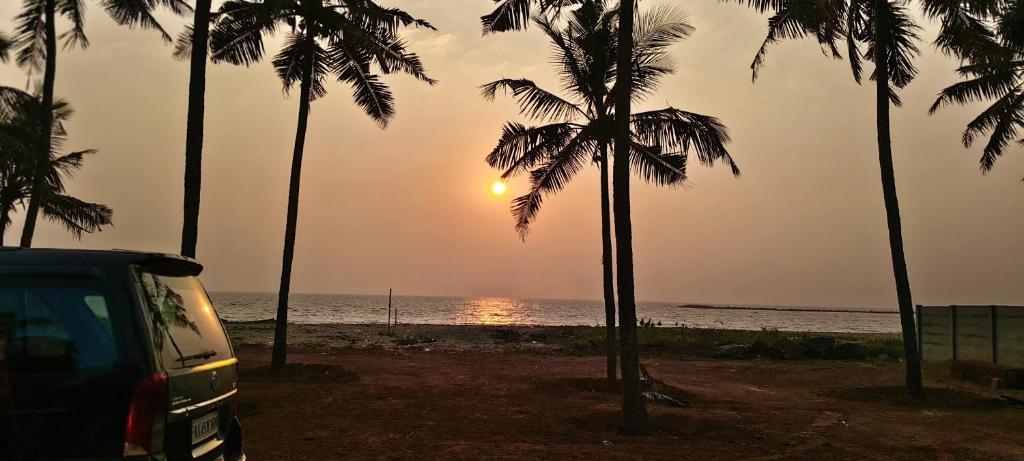 a van parked on a beach with palm trees at Agastya Beach House in Ullāl