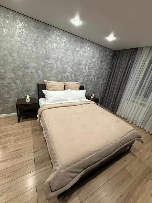 a bedroom with a large bed and a wall at Two-room apartment in Astana