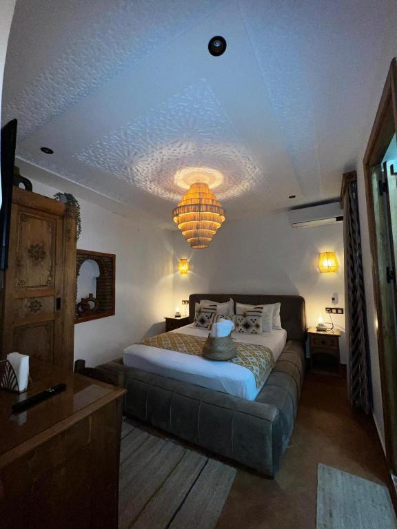 a bedroom with a bed and a couch and a chandelier at Riad abi khancha in Chefchaouen