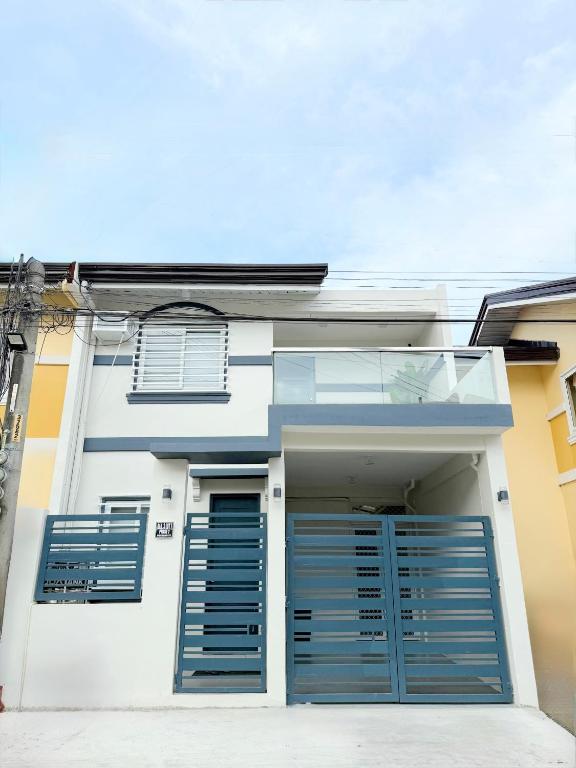 a white house with blue doors and windows at The Tuscan Townhouse in Tarlac