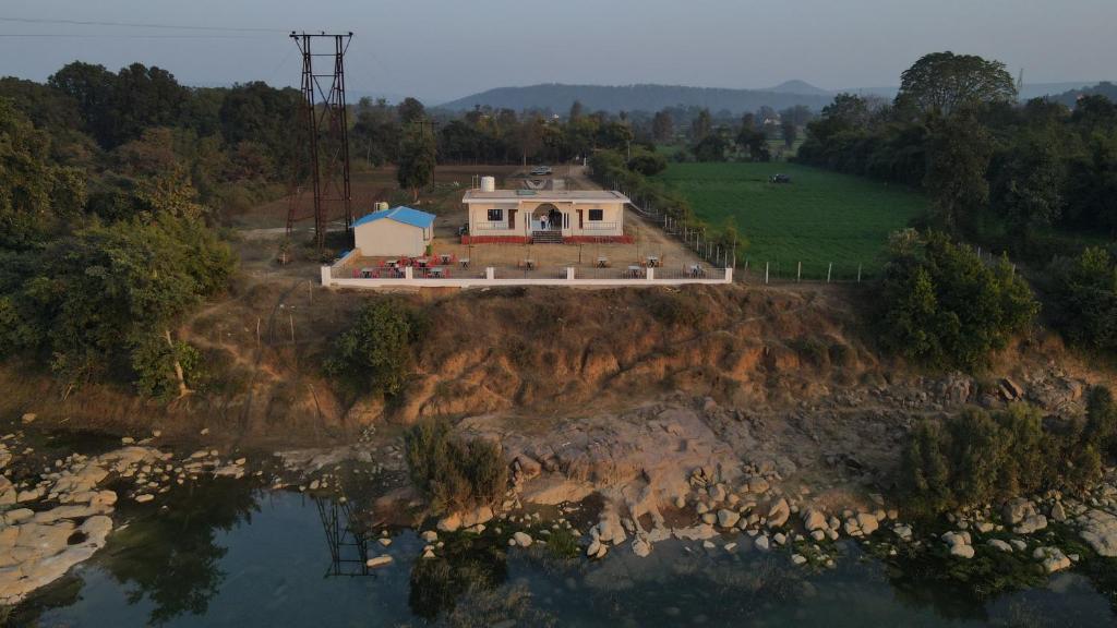 a house on a hill next to a body of water at Monkey River Resort Madla in Rājgarh