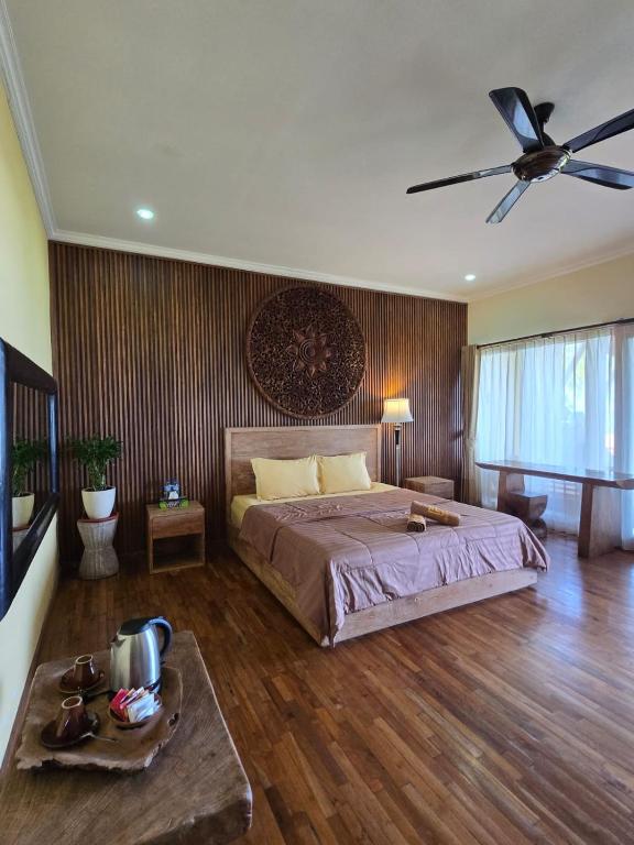 a bedroom with a bed and a ceiling fan at AgaLiving Medewi in Pulukan