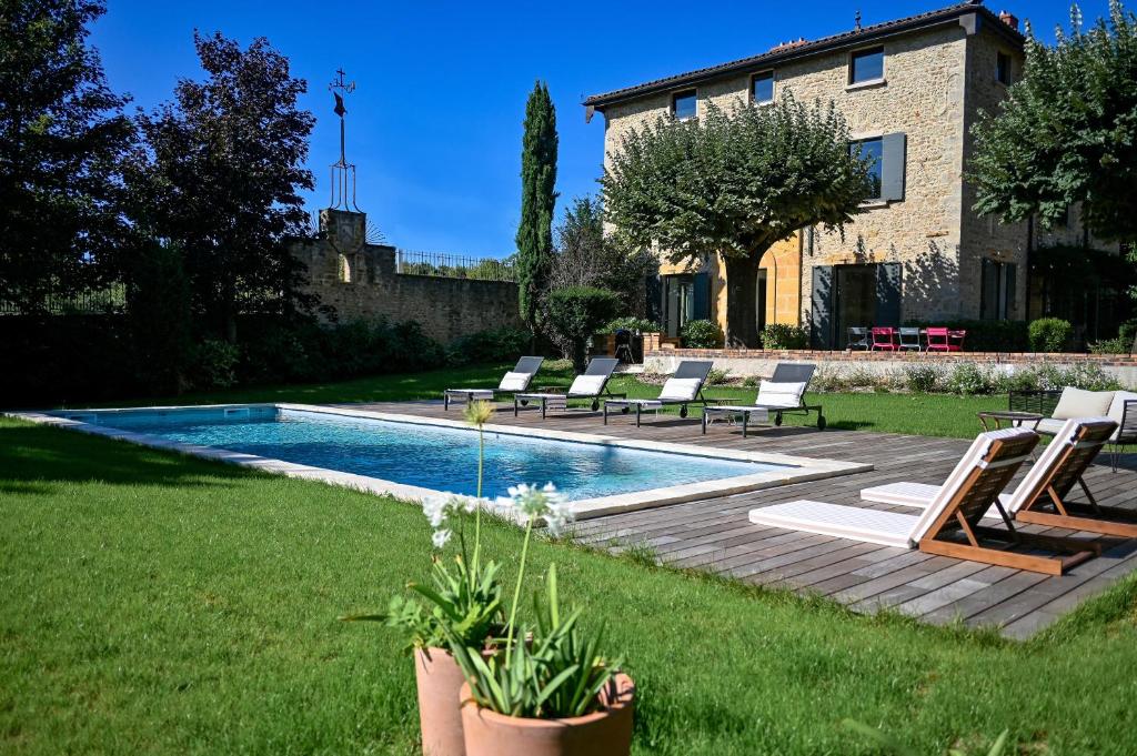 a backyard with a swimming pool with chairs and a house at La Maison et l'Orangerie in Saint-Jean-des-Vignes