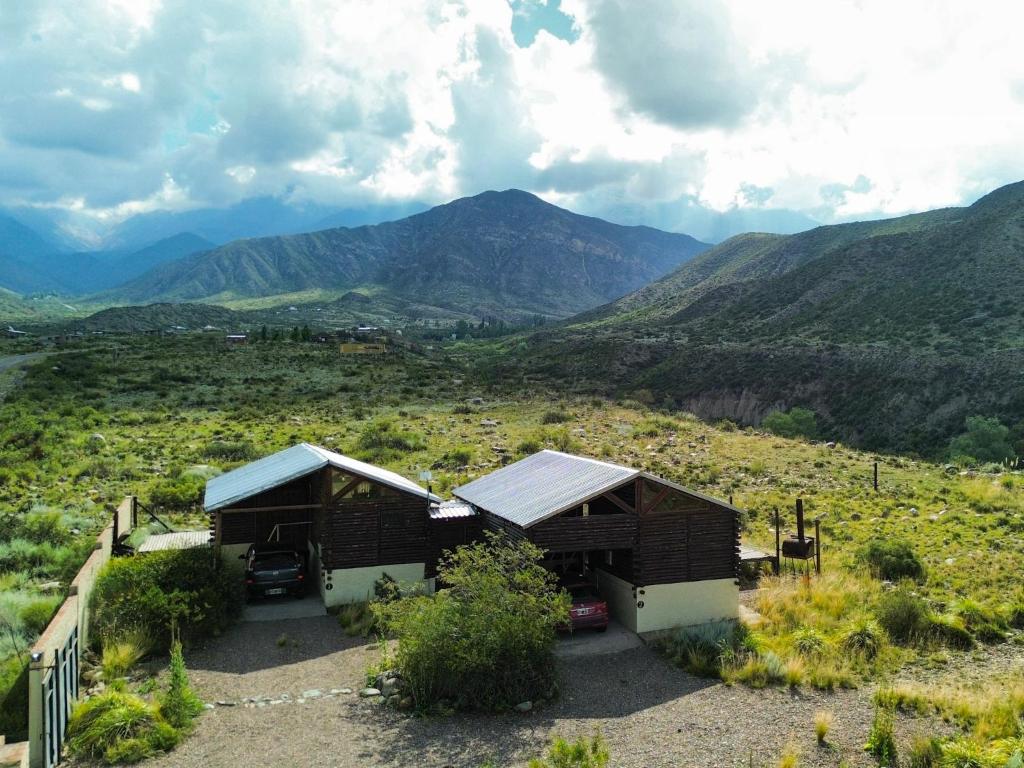 a small house in a field with mountains in the background at Aventurados in Potrerillos