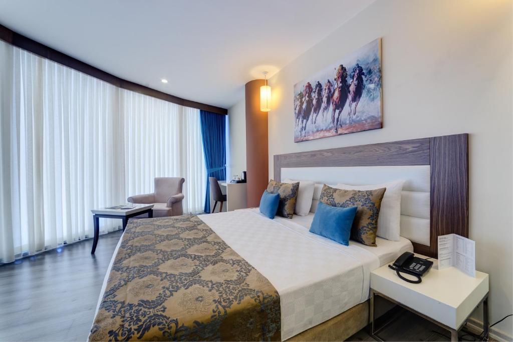 um quarto de hotel com uma cama grande com almofadas azuis em Forum Suite Otel em Mersin