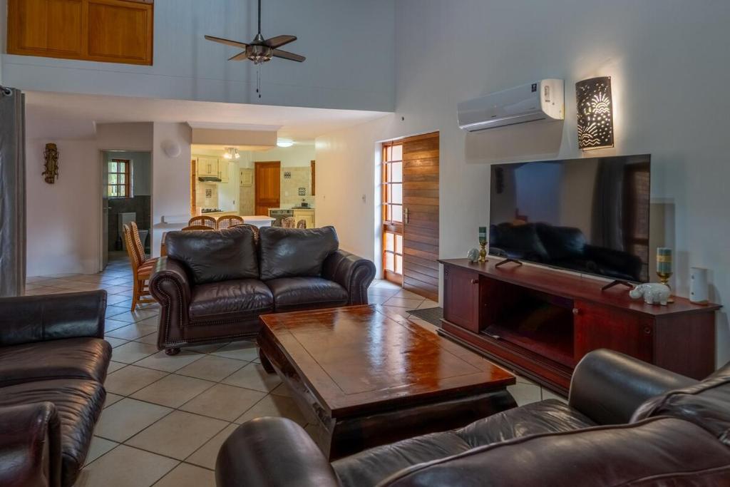 a living room with leather furniture and a flat screen tv at Kruger Park Lodge Unit No 219 in Hazyview